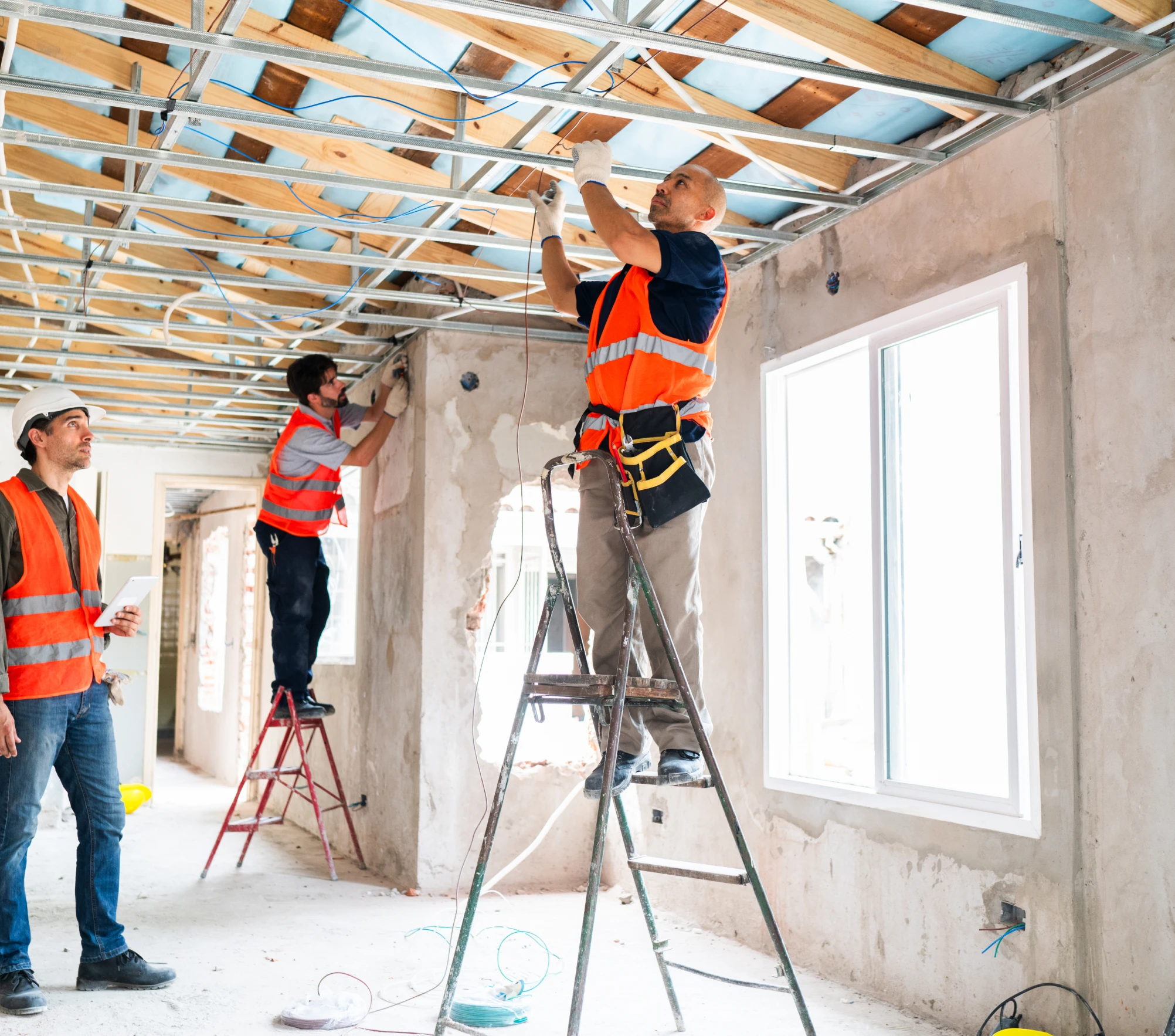 Workers installing ceiling framework in building.
