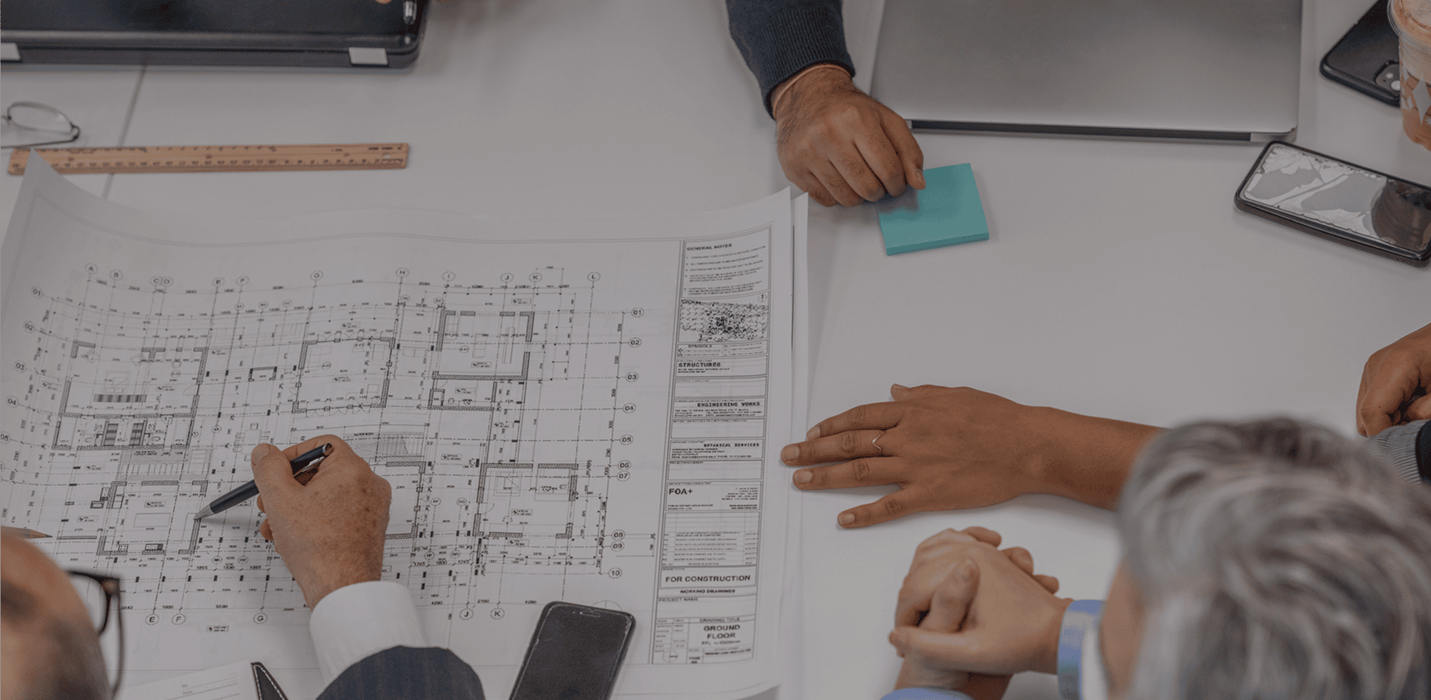 People discussing architectural blueprint on table.