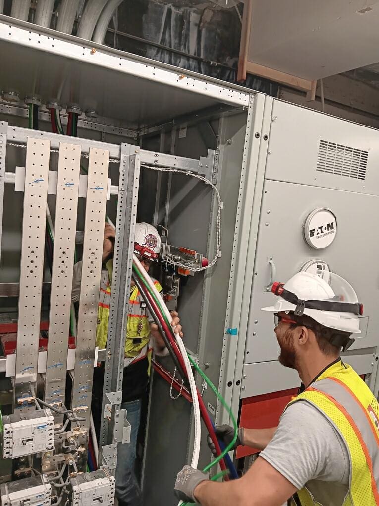 Technicians installing cables in control cabinet