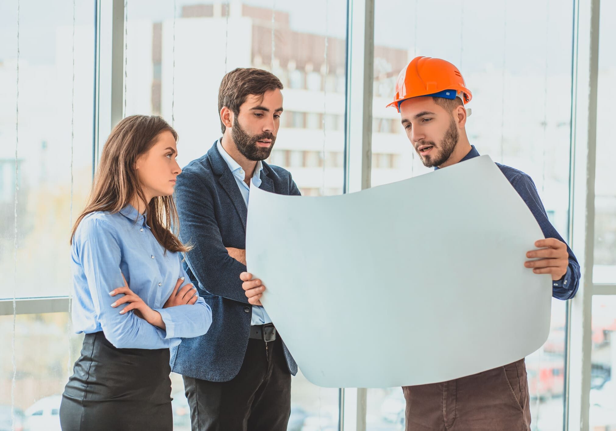 Three people discussing architectural plans indoors.